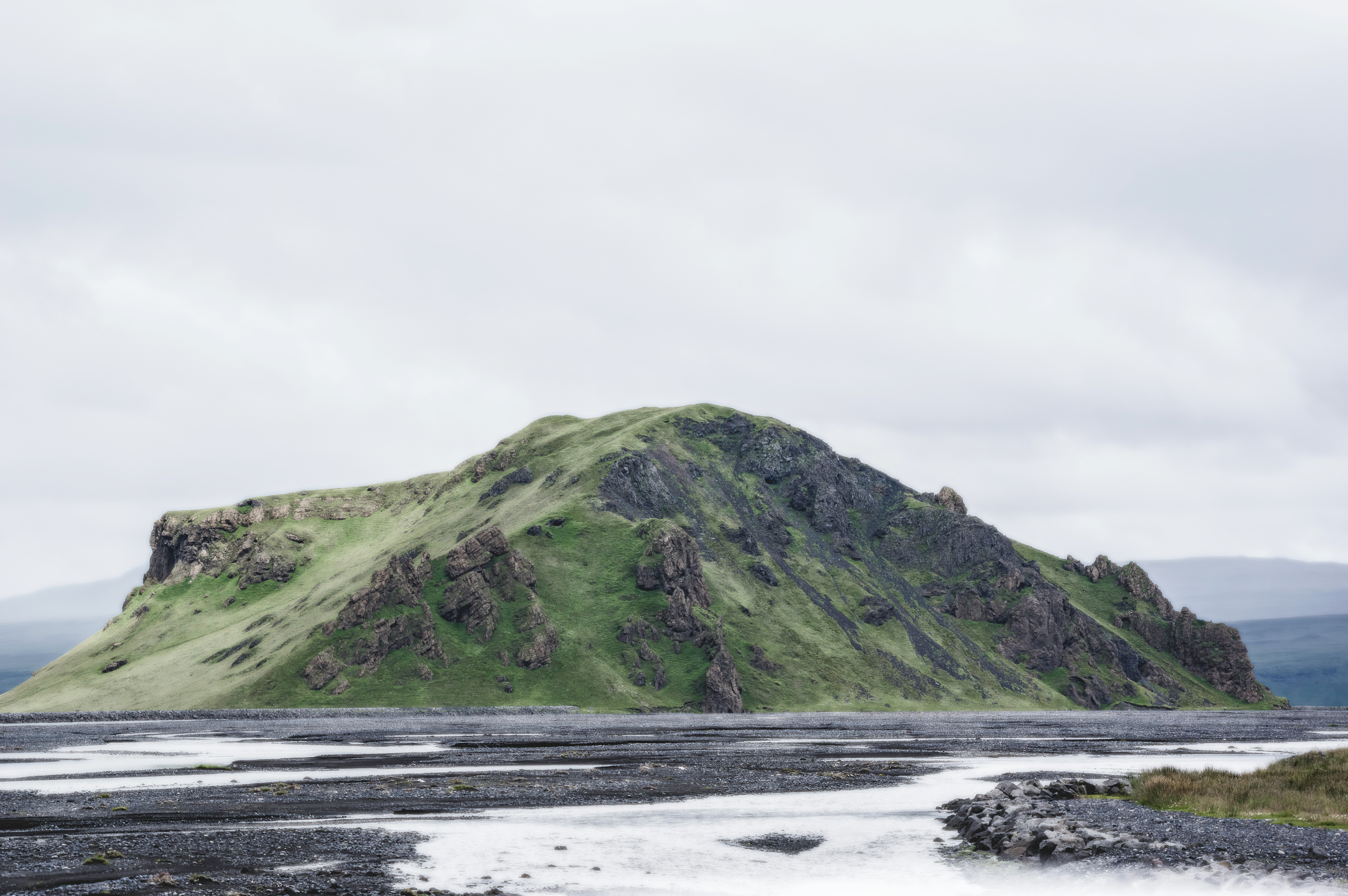 mountain beside sand with cloudy sky